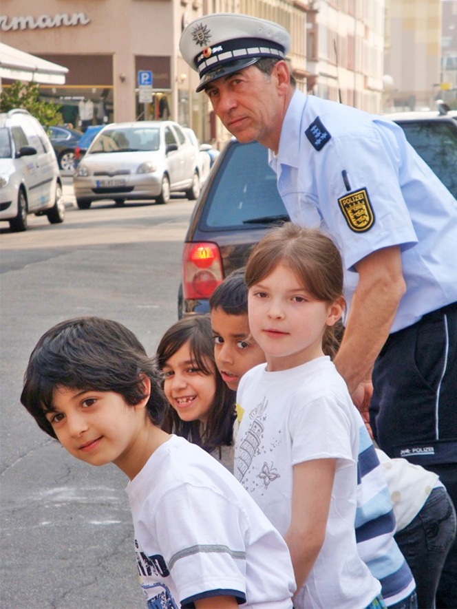 Schulwegesicherheit: Polizist und Kinder überqueren eine Straße